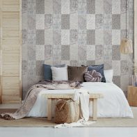 Brown and orange pillows on white bed in natural bedroom interior with wicker lamp and wooden bedside table with vase